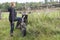 Mature joyful countrywoman standing with dirt motorcycle on rural road, copyspace