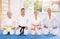 Mature judo practitioners in kimono sitting in seiza pose in sports hall