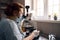 Mature lab assistant in mask looks into microscope researching sample at workplace