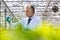 Mature male biochemist holding chemical in test tube with pipette in plant nursery