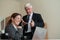 A mature male boss praises a subordinate. A woman in a suit works at a laptop at a desk. Friendly colleagues chat in the