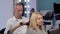 Mature male hairdresser blow drying hair of a female client at the salon