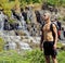 Mature man with backpack at waterfall pongour close up