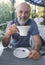 Mature man with big white cup. Open veranda of restaurant