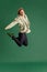 Mature man in casual clothes emotionally jumping against green studio background. News, sales, surprise