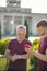 Mature man checking smartwatch with young male holding smartphone