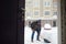 A mature man clean path near house from snow during strong blizzard. Person shoveling snow out of the driveway. Huge snowdrifts.