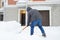 A mature man clean path near house from snow during strong blizzard. Person shoveling snow out of the driveway. Huge snowdrifts.