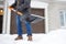 A mature man clean path near house from snow during strong blizzard. Person shoveling snow out of the driveway. Huge snowdrifts