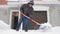 A mature man clean path near house from snow during strong blizzard. Person shoveling snow out of the driveway. Huge snowdrifts. D