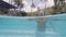 Mature man entering in water swimming pool by stairs in resort hotel underwater view. Adult man swimming in outdoor pool