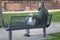 Mature man with face mask in his hand sitting on a park bench