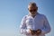 Mature man, gray haired, bearded, sunglasses, white shirt, checking social networks on his cell phone, outdoors. Concept