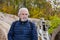 mature man with graying hair and beard moustache at waterfall with autumn forest, copy space, nature