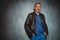 Mature man in leather jacket standing in gray studio