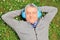 Mature man lying on grass with headphones, listening to music