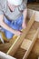 Mature man measuring wooden shelf with reel while making shelf u