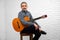 Mature man posing in studio with guitar.