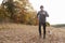 Mature Man Running Around Autumn Field With Pet Bulldog