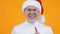 Mature man in santa hat showing quiet gesture, holiday surprise, secret party