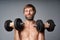 Mature man shirtless standing with dumbbells smiling