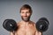Mature man shirtless standing with dumbbells smiling