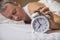 Mature man sleeping in bed with alarm clock in foreground at bed