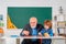 Mature man teacher and pupil on balckboard background. Senior teacher in classroom with elementary school kid. Science