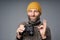 Mature man in warm sweater and knitted hat holding binoculars gesturing OK