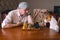 Mature man wearing bandana hard looking on his basenji dog rival while sitting at the table in a chess family tournament