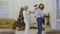 Mature man wearing santa hat dancing with wife at home near Christmas tree