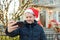 Mature man wearing Santa hat making selfie near his decorated home. Owner decorated his house and yard with garlands for Christmas