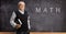 Mature math teacher with a book in front of a blackboard with formulas