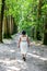 Mature Mexican woman in a white dress walking away from the camera on a dirt path between trees in the forest