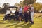 Mature And Mid Adult Couples Standing By Golf Buggy Checking Score Cards Together