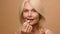Mature middle-aged elderly woman model makeup hygienic lipstick applying moisturizing lip balsam natural beauty face