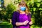 Mature middle-aged woman in blue medical mask, washes hands with a gel antiseptic spray over nature park background