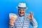 Mature middle east man with mustache wearing elegant vintage style holding euros banknotes doing ok sign with fingers, smiling