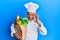 Mature middle east man professional chef holding bag of groceries doing ok sign with fingers, smiling friendly gesturing excellent