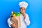 Mature middle east man professional chef holding bag of groceries serious face thinking about question with hand on chin,