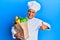 Mature middle east man professional chef holding bag of groceries smiling happy and positive, thumb up doing excellent and