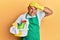Mature middle east man wearing cleaner apron holding cleaning products stressed and frustrated with hand on head, surprised and