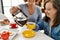 Mature mother and down syndrome daughter having coffee and lunch at home