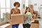 Mature mother and down syndrome daughter moving to a new home, standing by cardboard boxes