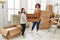 Mature mother and down syndrome daughter moving to a new home, standing by cardboard boxes holding welcome door mat