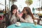 Mature mother and her young daughter sit together in cafe or restaurant. Girl worry about her mom`s health. Mature woman