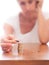 Mature older woman putting coins into a pile, heap, on table. Defocussed high key background. Poverty concept, counting