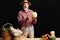 Mature owner of eco farm, stands nearby table with raw vegetables, eggs and hen