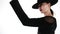 Mature pretty woman posing with black hat on white background. Femme fatale, stylish outfit, beautiful make-up. Camera