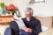 Mature retired man with feet up sitting on a sofa reading a newspaper